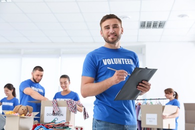 Male volunteer with clipboard listing donations indoors