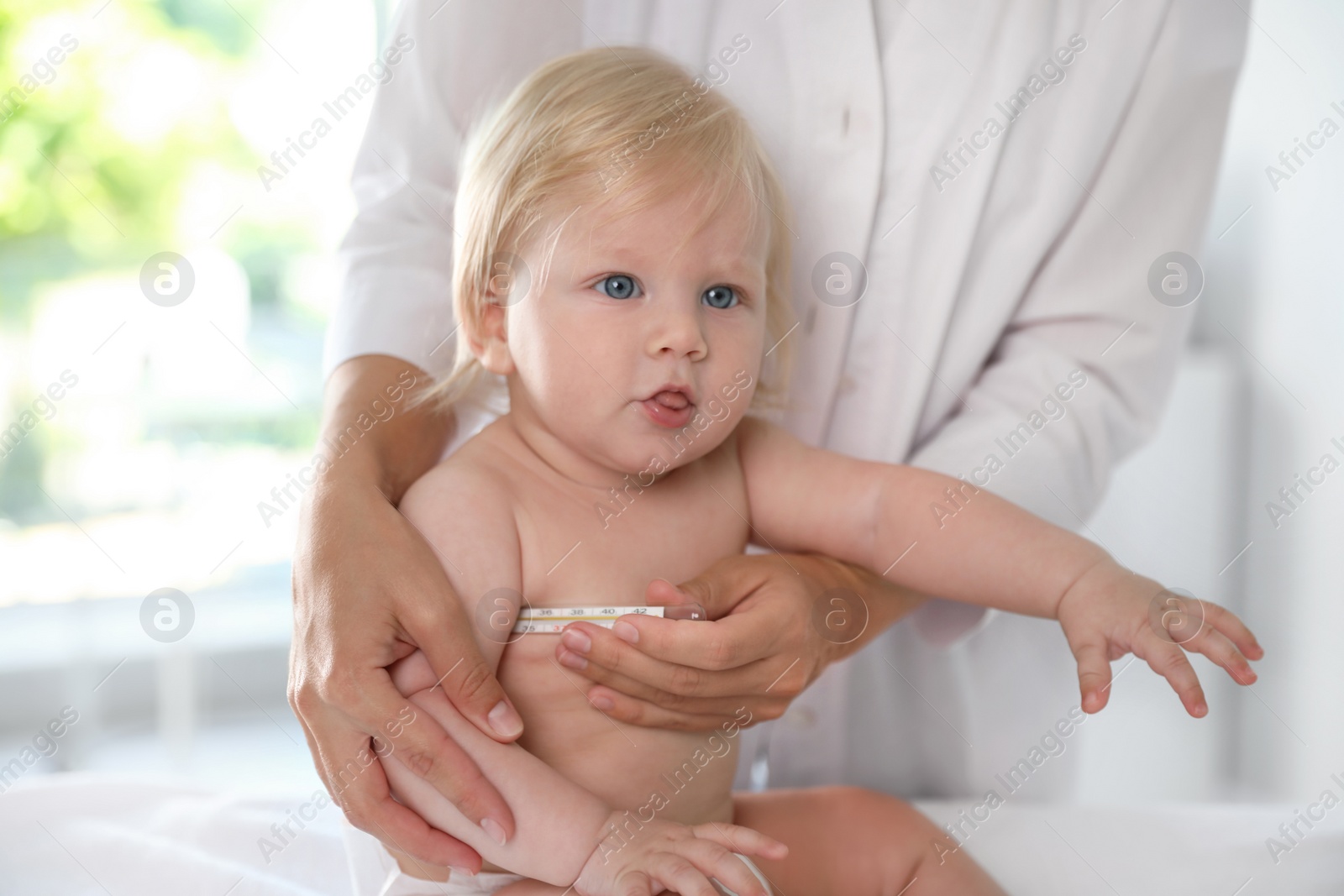 Photo of Pediatrician checking baby's temperature in hospital, closeup. Health care