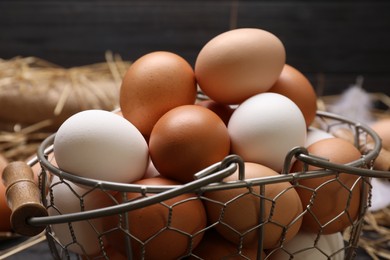 Photo of Fresh chicken eggs in metal basket on table, closeup