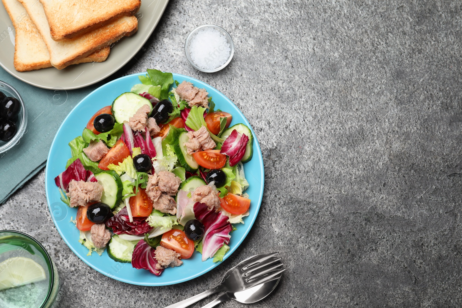 Photo of Plate of delicious salad with canned tuna and vegetables served on grey table, flat lay. Space for text