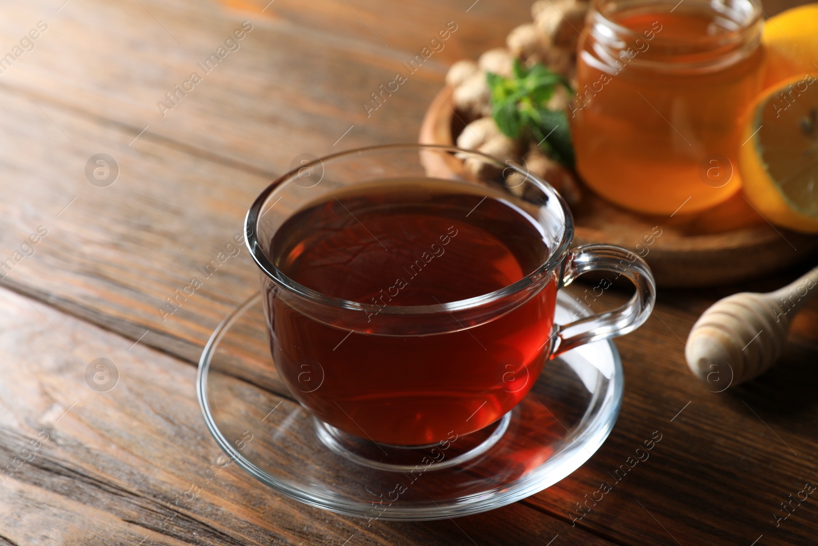 Photo of Cup of delicious ginger tea and ingredients on wooden table