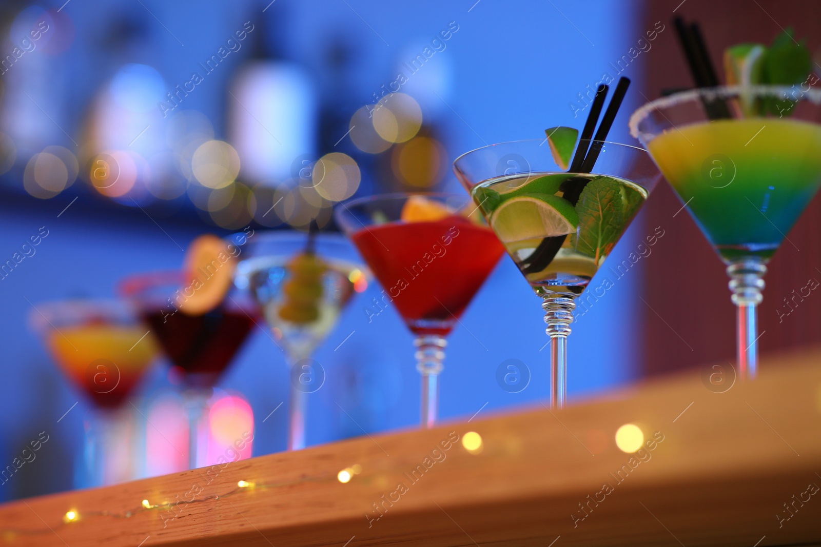 Photo of Different martini cocktails on table in bar, closeup with space for text