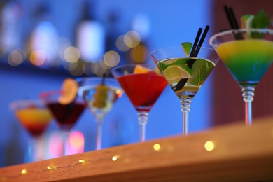 Photo of Different martini cocktails on table in bar, closeup with space for text