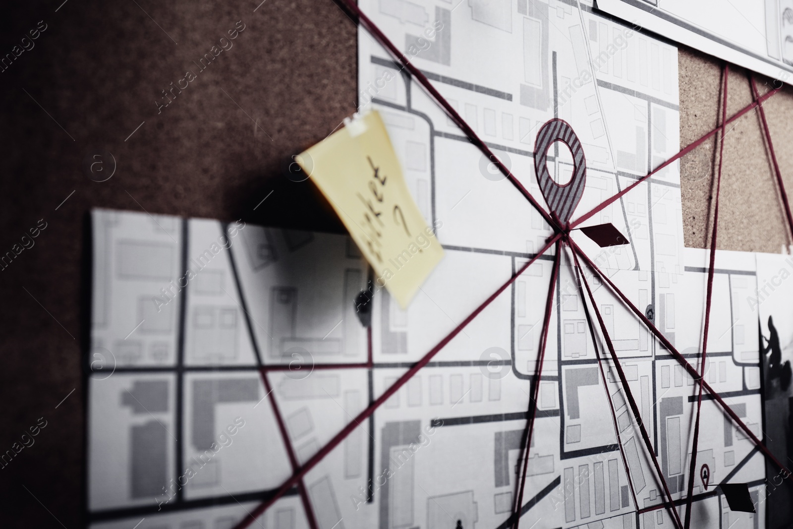 Photo of Detective board with map, sticker and red threads, closeup