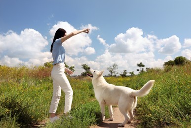 Photo of Teenage girl training her white Swiss Shepherd dog in field
