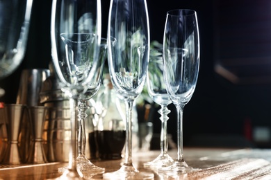 Photo of Different empty clean glasses on counter in bar, closeup