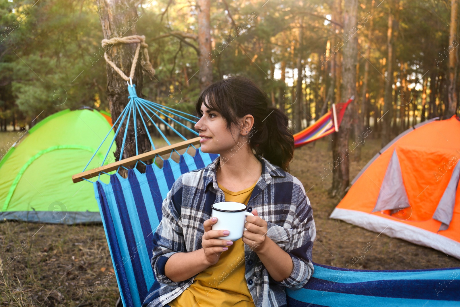 Photo of Woman with drink resting in comfortable hammock outdoors