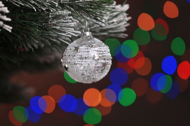 Photo of Beautiful holiday bauble hanging on Christmas tree against blurred festive lights, closeup