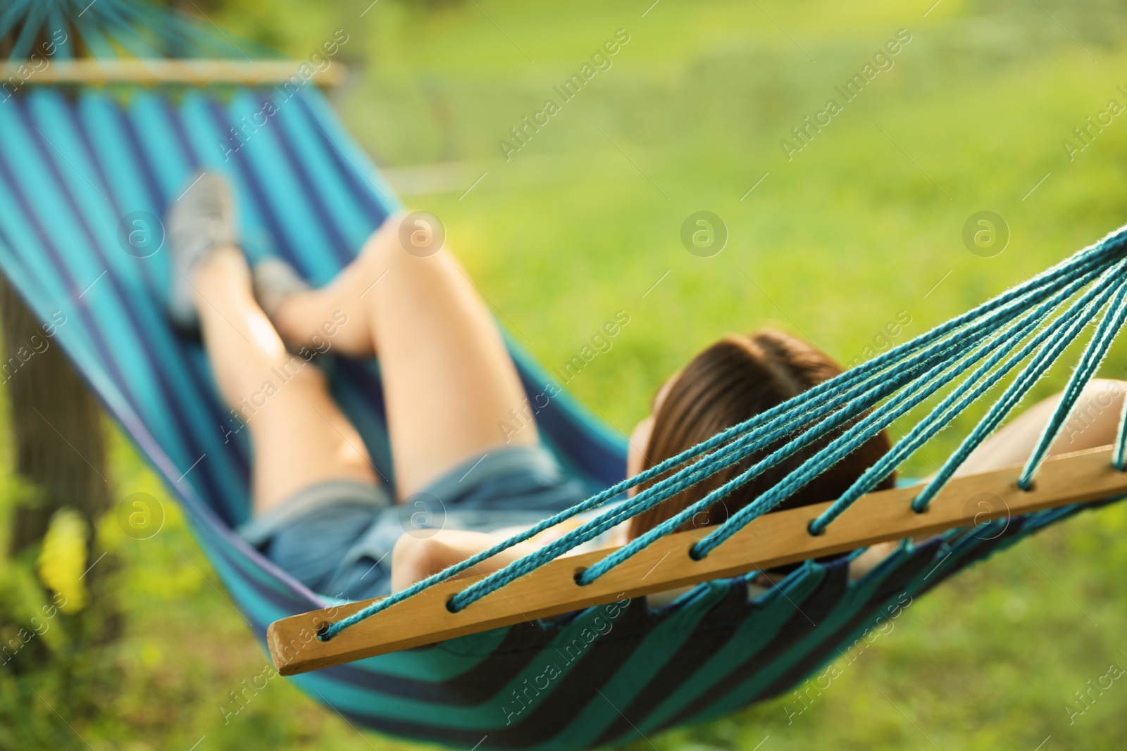 Photo of Young woman resting in comfortable hammock at green garden