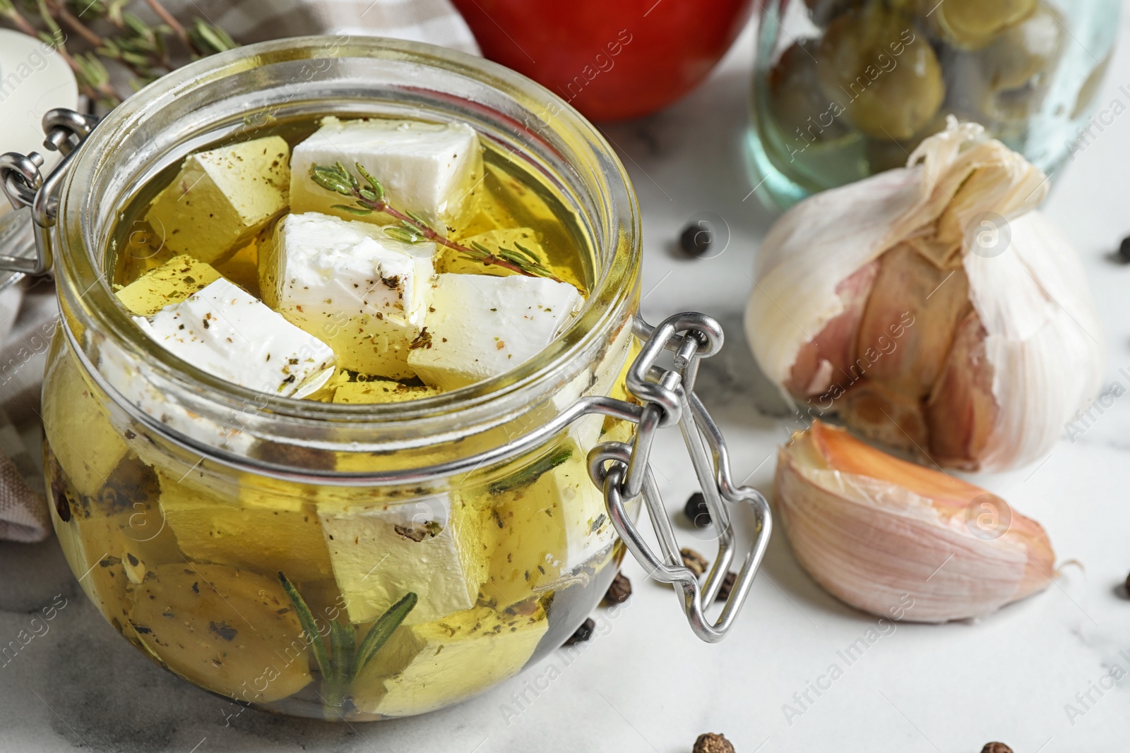 Photo of Composition with pickled feta cheese in jar on white marble table