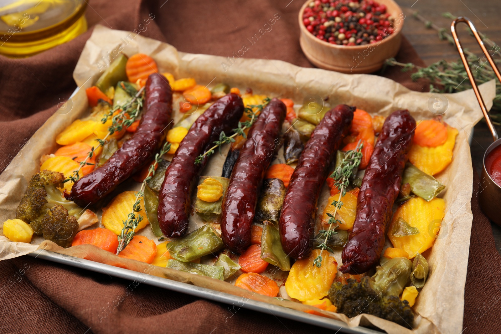 Photo of Baking tray with delicious smoked sausages and vegetables on table, closeup