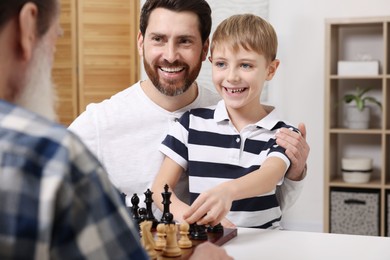 Family playing chess together at table in room