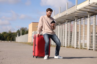 Photo of Being late. Worried man with red suitcase and passport outdoors