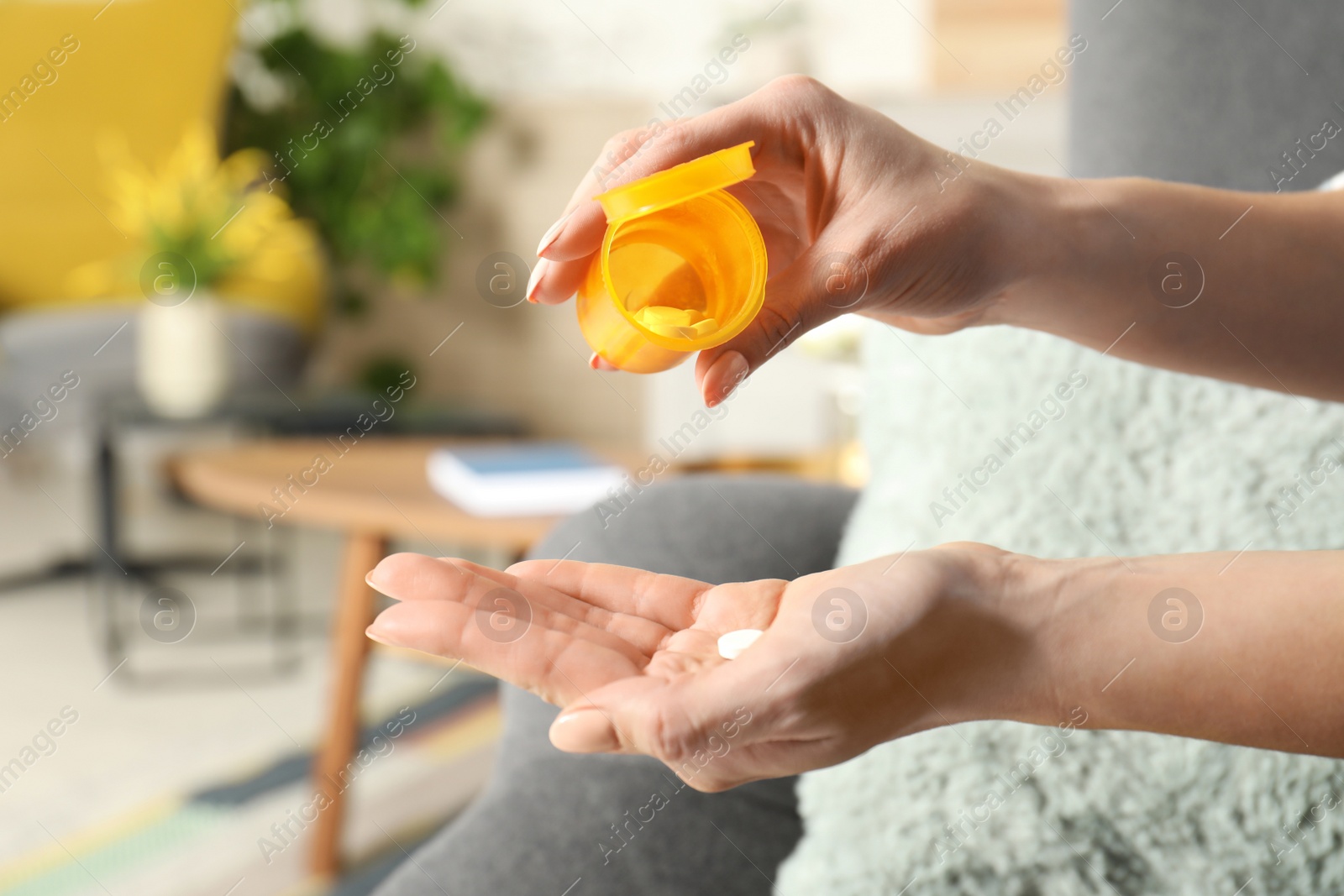 Photo of Woman pouring pills from bottle into hand indoors, closeup