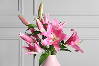 Photo of Beautiful pink lily flowers in vase against light wall