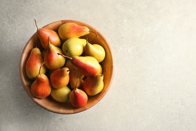 Bowl with ripe pears on light background, top view. Space for text