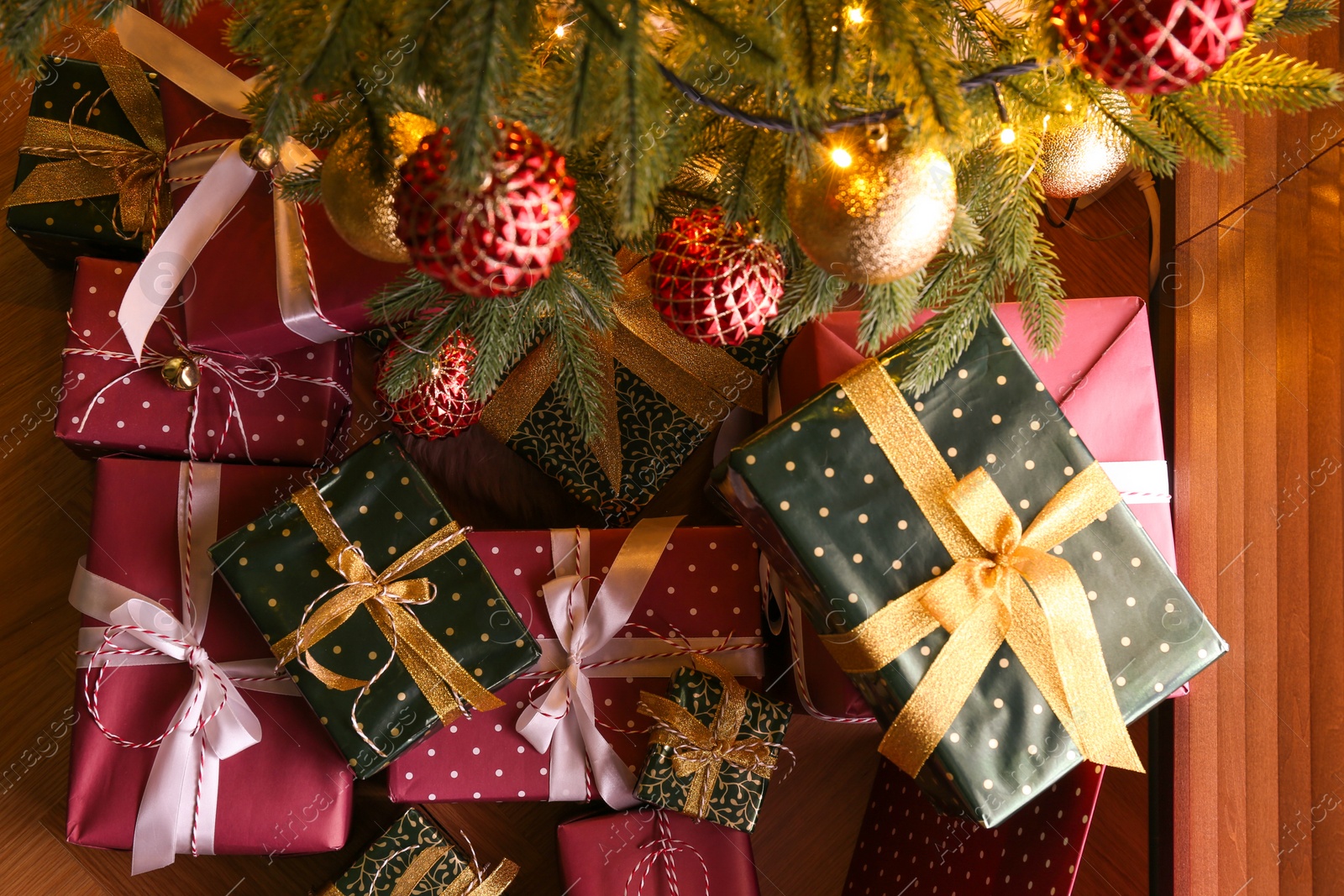 Photo of Pile of gift boxes near Christmas tree indoors, flat lay