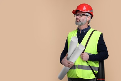 Photo of Architect in hard hat holding drafts on beige background. Space for text