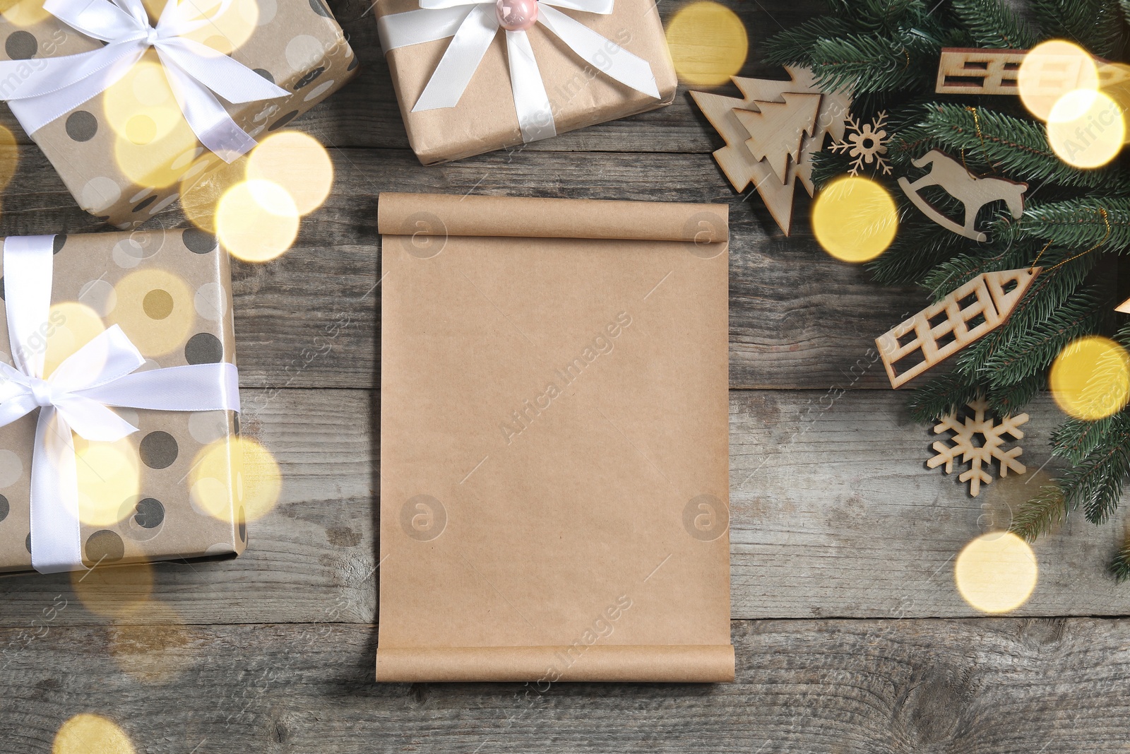 Photo of Flat lay composition with blank paper sheet, gift boxes and Christmas decor on wooden table, space for text. Letter to Santa