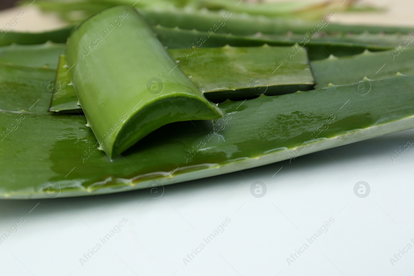 Photo of Fresh cut juicy aloe vera leaves on white table, closeup