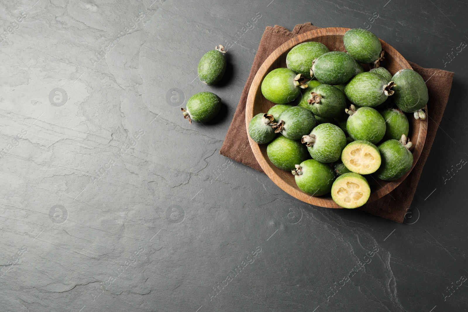 Photo of Delicious fresh feijoas on black table, flat lay. Space for text