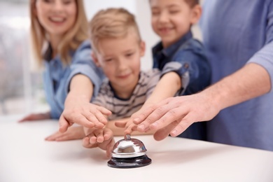 Photo of Family ringing service bell on reception desk in hotel