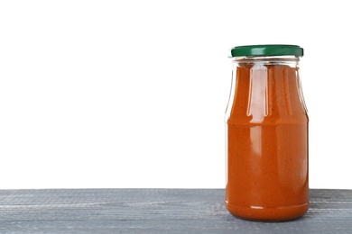 Photo of Jar of butternut squash spread on blue wooden table against white background. Pickled food