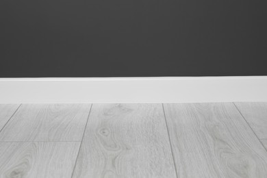 Photo of White plinth on laminated floor near black wall indoors