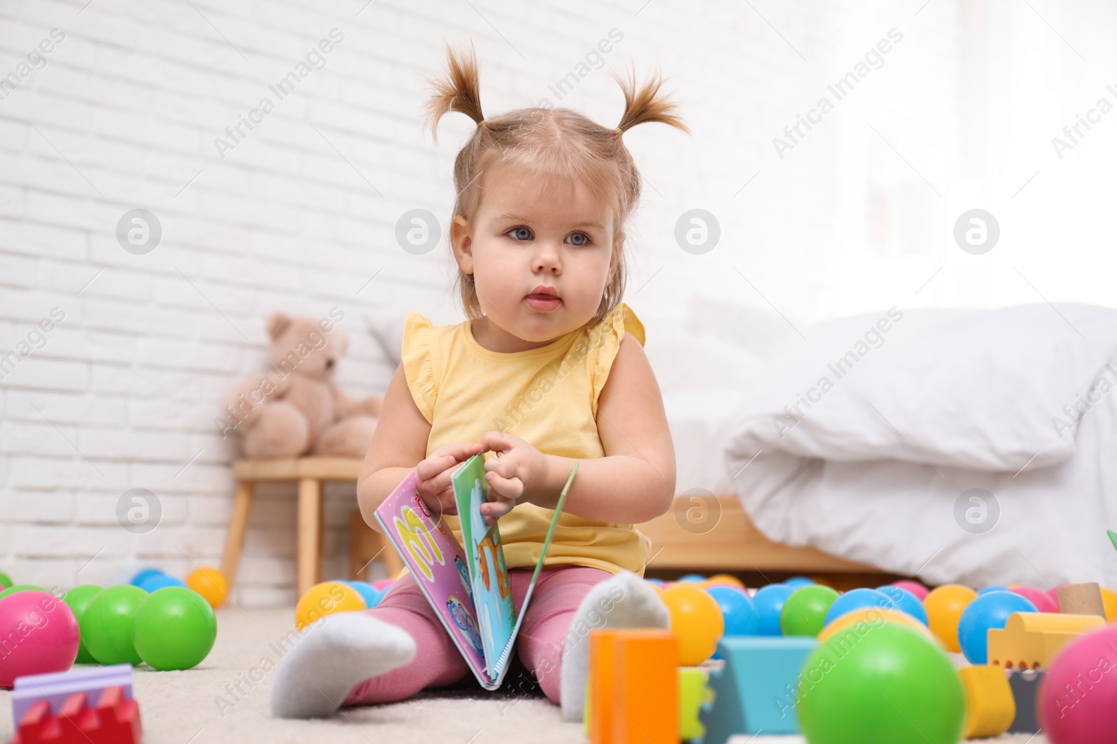 Photo of Cute little child with book playing on floor