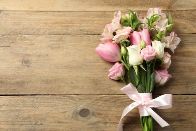 Photo of Happy Mother's Day. Bouquet of beautiful flowers tied with pink ribbon on wooden table, top view. Space for text