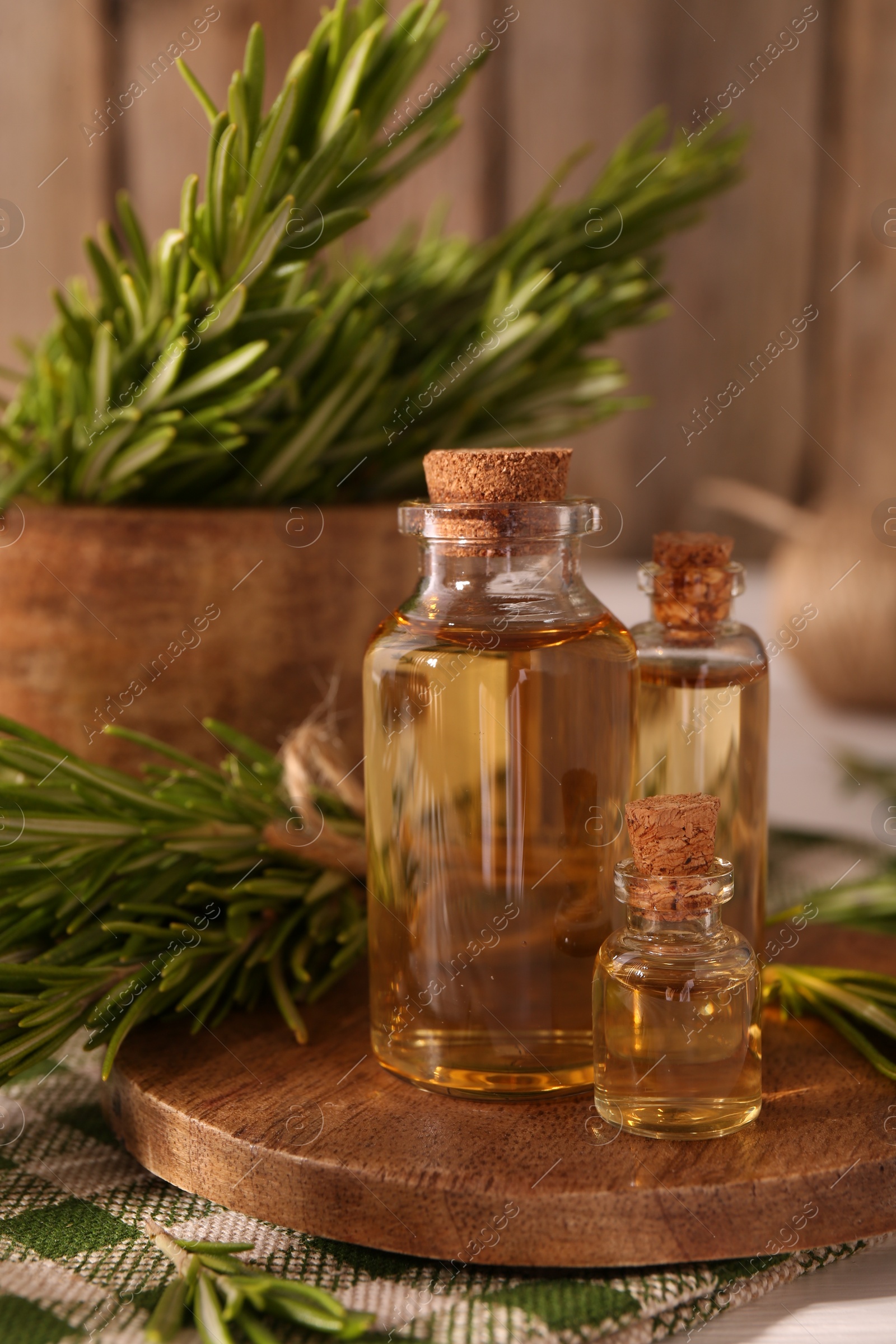 Photo of Essential oil in bottles and rosemary on table