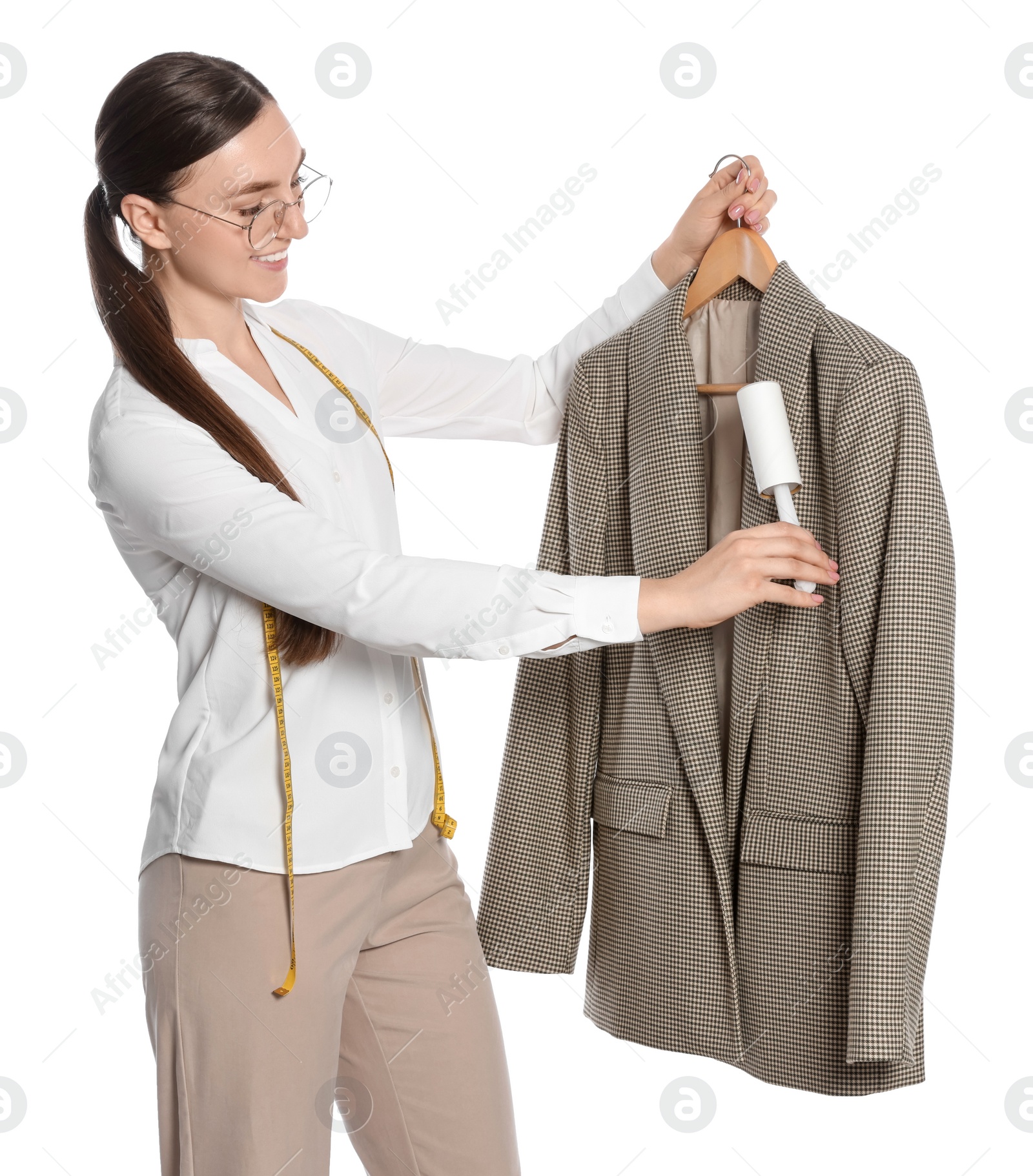 Photo of Young woman cleaning suit with lint roller on white background