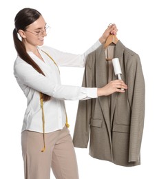 Young woman cleaning suit with lint roller on white background