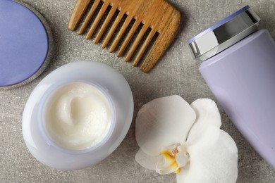 Photo of Hair care cosmetic products, orchid flower and comb on grey table, flat lay
