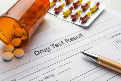 Photo of Drug test result form, pills and pen on light table, closeup