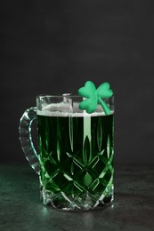 Photo of St. Patrick's day celebration. Green beer with decorative clover leaf on grey table. Space for text