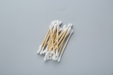 Many wooden cotton buds on light grey background, flat lay