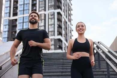 Photo of Healthy lifestyle. Happy couple running on steps outdoors, low angle view