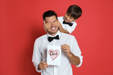 Photo of Little boy greeting his dad with Father's Day on red background