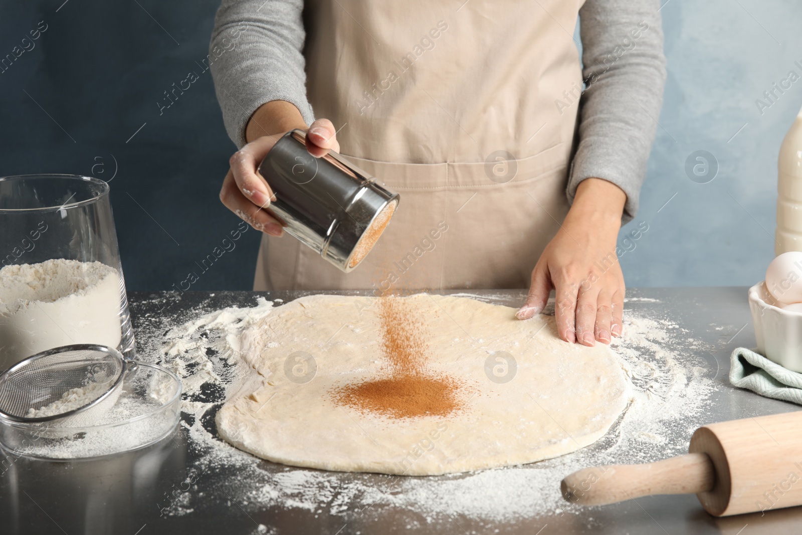 Photo of Woman making cinnamon rolls at table, closeup