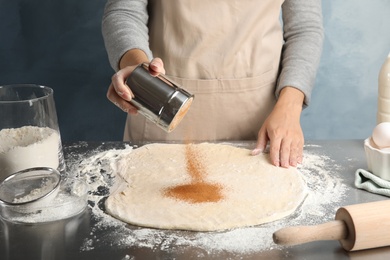 Woman making cinnamon rolls at table, closeup