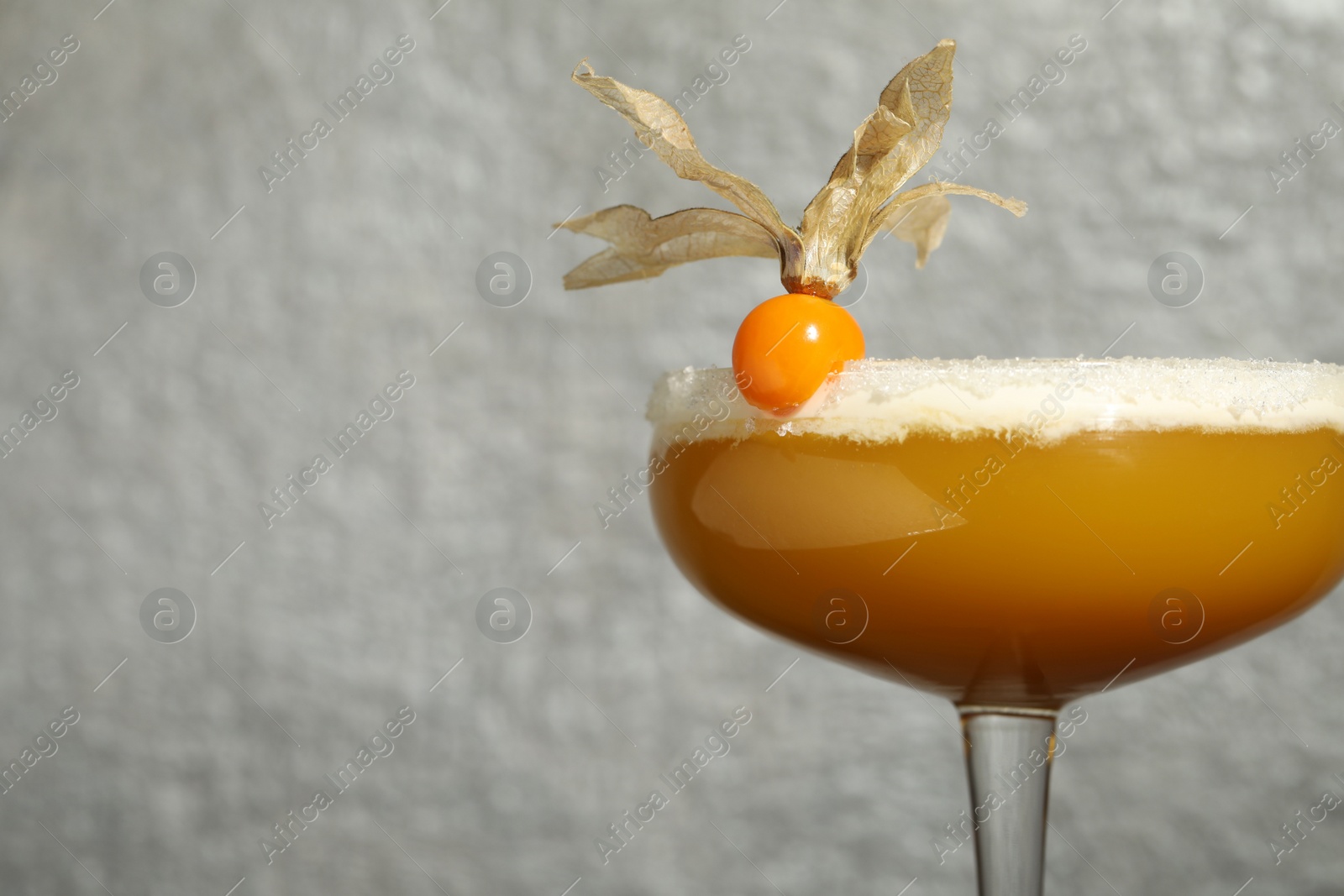 Photo of Refreshing cocktail decorated with physalis fruit on grey background, closeup. Space for text