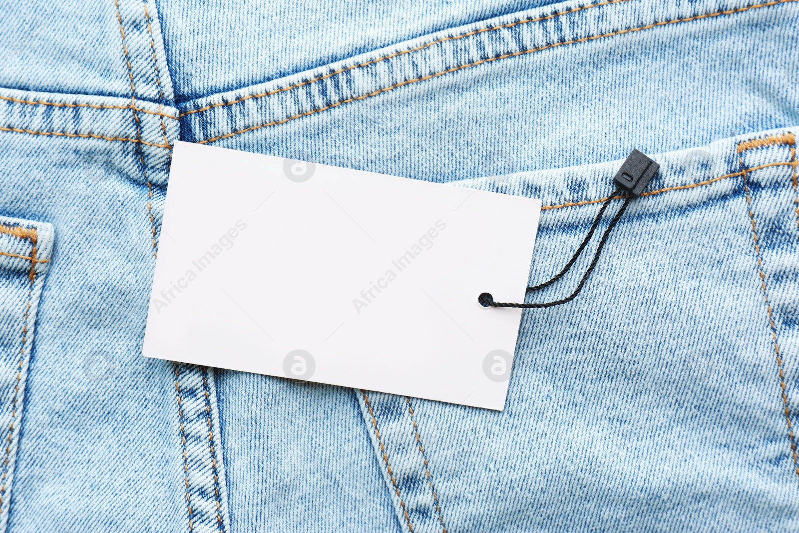 Photo of Blank tag on jeans, top view. Space for text