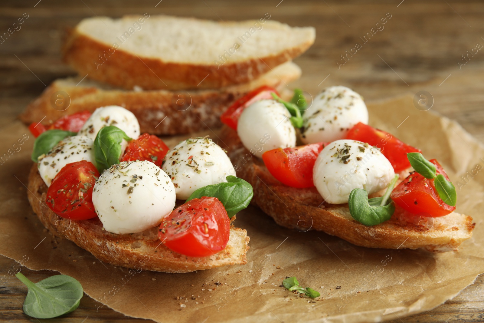 Photo of Delicious sandwiches with mozzarella, fresh tomatoes and basil on wooden table