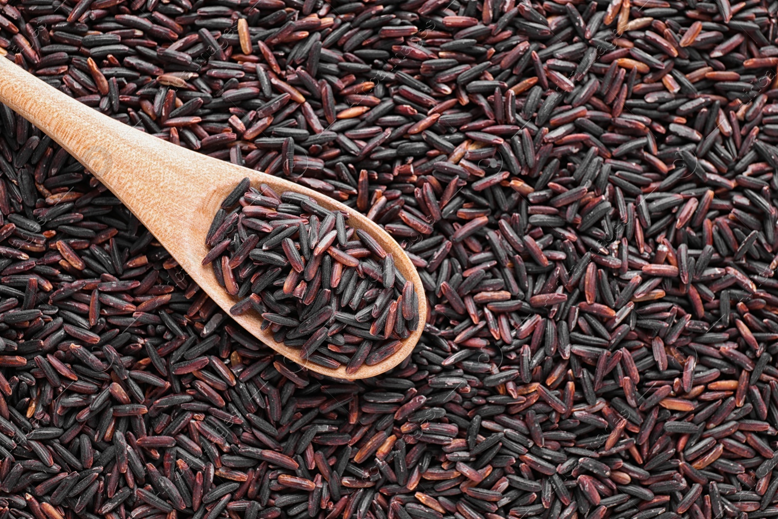 Photo of Pile of brown rice with spoon, top view. Space for text