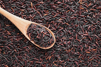 Photo of Pile of brown rice with spoon, top view. Space for text