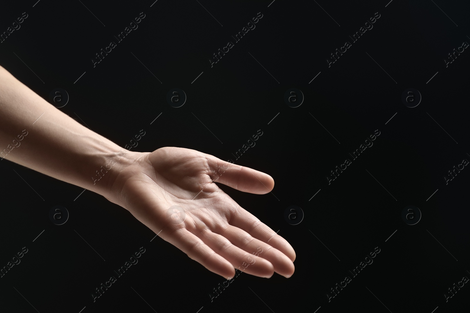 Photo of Woman holding something in hand on black background, closeup. Space for text