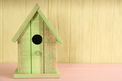 Photo of Beautiful bird house on pink wooden table, space for text