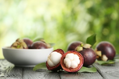 Photo of Delicious ripe mangosteen fruits on wooden table outdoors