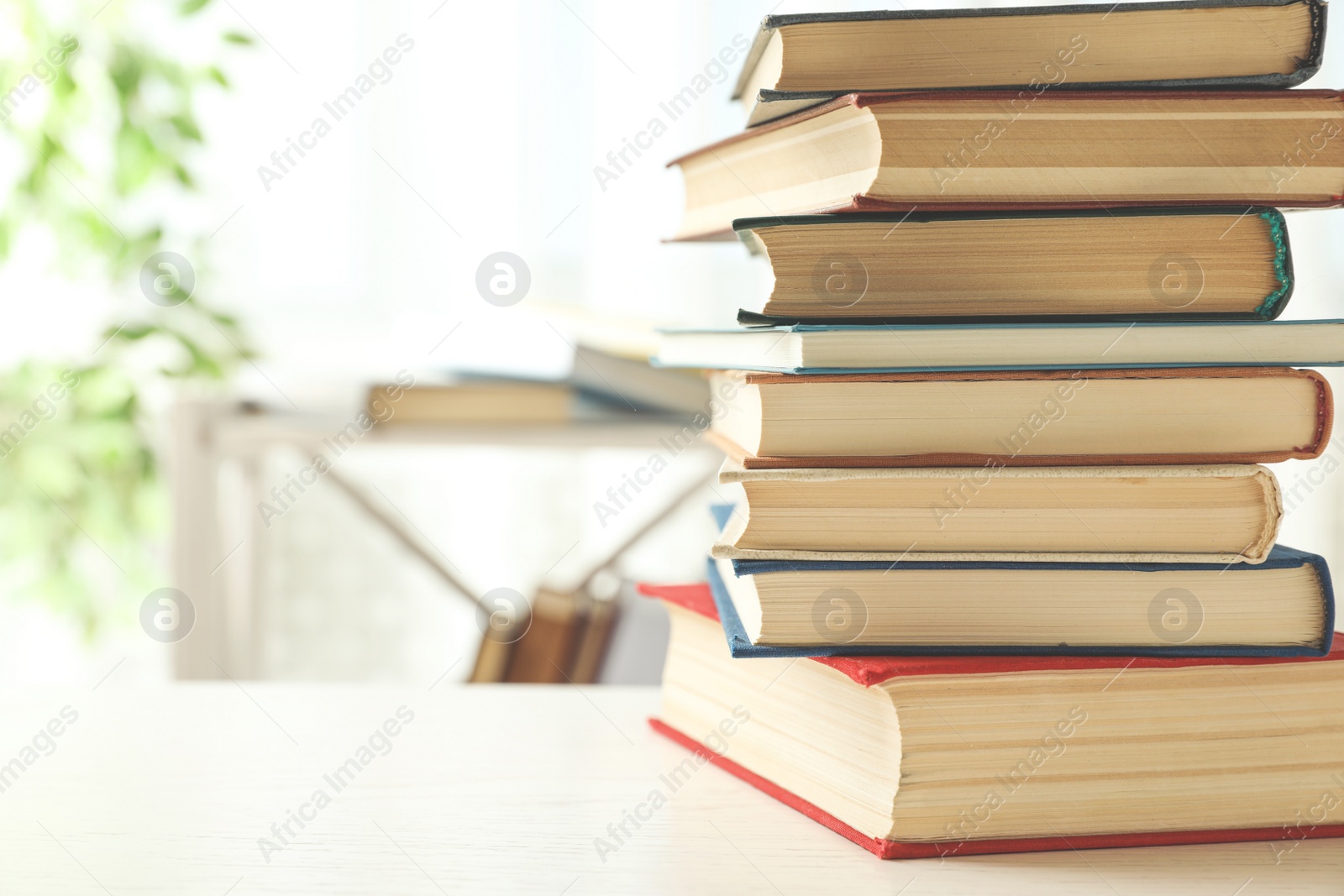 Photo of Stack of hardcover books on white wooden table indoors. Space for text